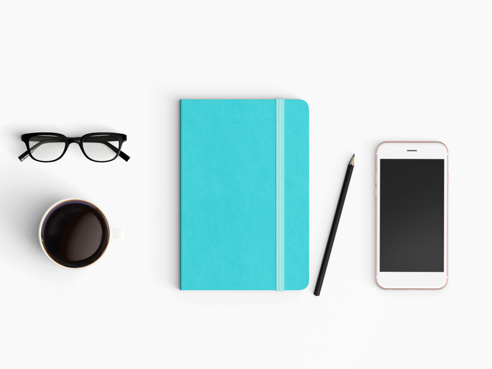  Modern office desk workplace with notebook diary, coffee cup, pencil and smartphone copy space on white desk background. Top view. Flat lay style.